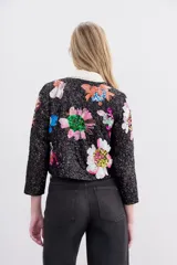 Saco corto negro con bordado de lentejuelas con forma de flores de colores. Tiene cuello redondo y ganchos invisibles al frente.