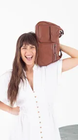 Bandolera color beige con correa ajustable, dos bolsillos frontales (uno con botón y otro con cierre) y un bolsillo trasero con cierre.