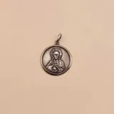 Dije redondo plateado con la imagen en relieve del Sagrado Corazón de Jesús.