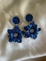 Aros colgantes con base circular azul con borde de strass y dije de flor azul con centro de strass.