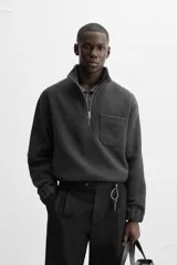 Sudadera gris oscuro de tejido polar con lana, corte relaxed fit, cuello alto con cierre de cremallera, manga larga, bolsillo tipo parche en el pecho y terminaciones elásticas.
