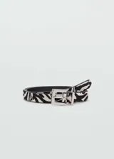 Cinturón de cuero con estampado animal print de cebra, hebilla cuadrada metálica plateada y forro de poliuretano negro.