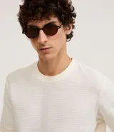 Remera de mangas cortas color crema, confeccionada con 50% algodón y 50% poliéster, con cuello redondo y tejido texturizado.