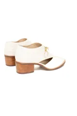 Zapato de cuero color blanco con textura reptil en el talón, corte lateral y hebilla dorada.