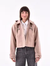 Campera corta color beige con capucha, cierre frontal con botones a presión y bolsillos laterales.
