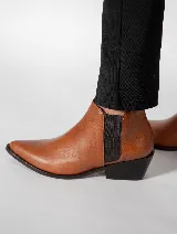 Botín de cuero color marrón claro, con elástico negro en los laterales, punta fina y taco cuadrado bajo color negro.