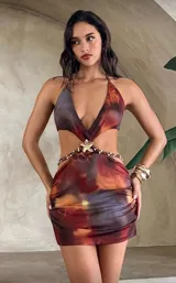 Minivestido con estampado abstracto en tonos marrones, naranjas y grises. Diseño con escote halter, espalda descubierta, abertura en la cintura y falda ajustada.