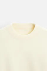 Jersey color crema de corte relajado, tejido con textura. Tiene cuello redondo, mangas largas y terminaciones en rib.