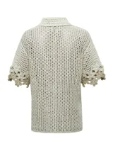 Chaleco tejido a crochet con diseño de flores en tonos beige y crudo, con cuello camisero y cierre frontal con botones de madera.