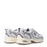 Championes New Balance 530 de mujer, color gris claro con detalles en blanco y beige. Presentan una capellada de malla transpirable con refuerzos sintéticos y entresuela con tecnología ABZORB.