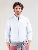 Camisa de hombre Oxford a rayas celestes y blancas, confeccionada en 93% algodón y 7% algodón reciclado. Corte regular fit, cuello button-down, cierre con botones, manga larga con puño simple y logo bordado en el pecho.