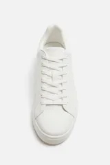 Zapatillas urbanas bajas color blanco, con cordones y suela plana.