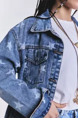 Campera de jean celeste con lavado ácido y estampado de estrellas blancas. Es de corte oversize.