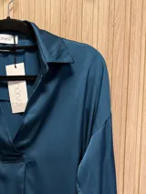Blusa de seda color fucsia, de corte holgado y mangas largas con puños abotonados.