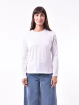 Remera blanca de manga larga con cuello redondo y detalle de tachas plateadas en hombros y mangas.