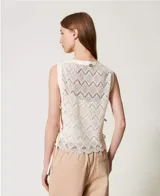Top sin mangas de encaje color crema, con cuello redondo y detalle de lazos en los laterales.