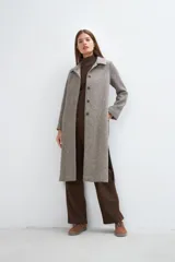 Tapado largo con cuello solapa y corte recto, color gris claro. Tiene cierre frontal con botones ocultos, tajos laterales y bolsillos escondidos en el corte lateral. Está forrado y confeccionado en lana fina sin teñir, diseñada exclusivamente por Don Baez. Hecho 100% en Uruguay.