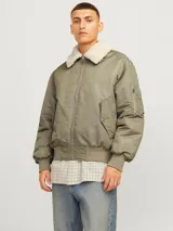 Campera bomber color verde oliva, de manga larga y cuello extendido. Tiene puños ribeteados, cierre con cremallera, bolsillo en la manga y bolsillos frontales con cierre de botón.