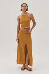 Top halter tejido texturizado en tono mostaza con tiras finas que se atan en la espalda.