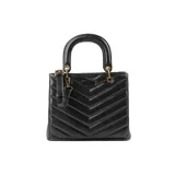 Cartera negra de símil cuero acolchado con diseño de líneas horizontales en forma de V. Tiene acceso con cierre y broches imantados, correa regulable, herrajes dorados y tres compartimentos internos. Se puede usar como bandolera o de mano.