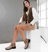 Bota corta de cuero color marrón con cierre lateral, suela de goma negra y hebilla decorativa.