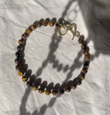 Gargantilla corta de piedras naturales ojo de tigre, con cierre de gancho metálico dorado.