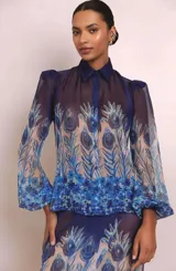 Camisa azul de organza estampada semitransparente, con doble cuello (cuello tradicional y cuello mao), mangas abullonadas con abertura y puños cerrados con botón. Incluye hombreras.