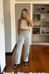 Pantalón de tiro alto con estampado de rayas verticales en color celeste y blanco. Presenta una cintura elástica fruncida, bolsillos laterales y un corte recto de calce holgado.