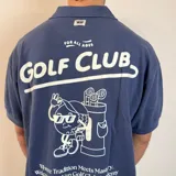Chomba color beige con cuello clásico, corte oversize, mangas cortas y bordados marrones con la inscripción "Golf Club" y otros motivos. 