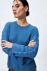 Sweater azul de punto canalé con trenzado en las mangas y lazo ajustable en los puños.