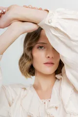 Blusa color crema con volados en el frente, detalle de puntilla y bordados florales en mangas.