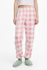 Pantalón de pijama largo de polar con cintura y puños elastizados, estampado a cuadros en tonos rosa y blanco.