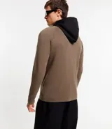 Cardigan de punto color marrón topo, con capucha negra contrastante y cierre frontal de cremallera negra. Presenta bolsillos laterales.