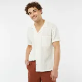 Camisa de manga corta color blanco hueso, de tejido calado con cuello solapa y bolsillo de parche en el pecho.