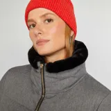 Campera puffer gris de franela con cuello de piel sintética negra, cierre frontal con cremallera dorada y bolsillos laterales.