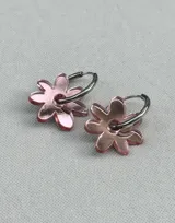 Par de aros colgantes plateados con dije de flor espejada color rosado.