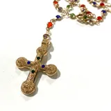 Collar tipo rosario con cadena dorada y cuentas de colores. Dije de cruz dorada con incrustaciones de gemas de colores.