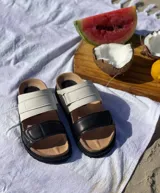 Sandalias bajas de cuero color tostado y beige, con doble tira ancha y plantilla de cuero.