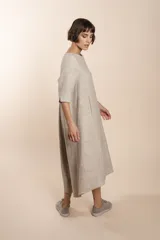 Vestido largo debajo de la rodilla, acampanado, color marrón, con cuello bote, bolsillos laterales y mangas 3/4 con detalle de tajo.