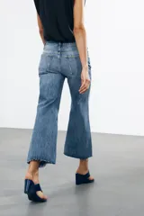 Pantalón de jean celeste de tiro bajo, corte flare, cropped y cinco bolsillos.