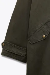 Trench color verde oscuro con cuello solapa combinado en pana marrón y manga larga. Detalle de acabados con trabillas y pinza en espalda. Bolsillos delanteros con solapa y botón a presión. Tejido encerado efecto lavado. Cierre frontal con botones a presión.