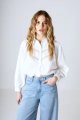 Camisa blanca de manga larga con detalles de encaje en el frente y cuello mao.