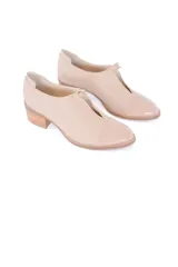 Zapatos de cuero color crema, con punta redondeada y detalle de abertura en forma de V en el empeine. Taco cuadrado de madera.