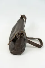 Cartera bandolera de cuero marrón oscuro con solapa y correa fina ajustable.