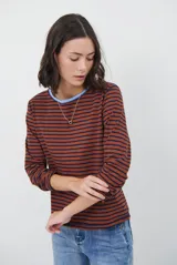 Remera de manga larga con diseño de rayas horizontales en azul y blanco, destacada por un cuello redondo en color bordó con costuras a la vista.