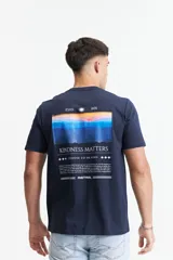 Remera azul marino de algodón con cuello redondo y mangas cortas. Estampado en la espalda con imagen de un atardecer, texto "Kindness Matters" y logo de Mistral.