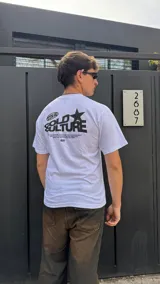 Remera blanca de algodón con estampado negro en la espalda que incluye el logo de la marca, una estrella y texto.