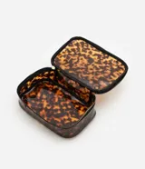 Neceser rectangular grande de plástico transparente con estampado de carey en tonos marrones. Tiene cierre de cremallera doble dorada, asa de mano negra y ribete negro.