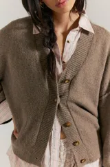 Cárdigan negro de silueta oversized, confeccionado en hilo de algodón suave con terminaciones acanaladas, escote en V, hombros caídos y mangas largas amplias.