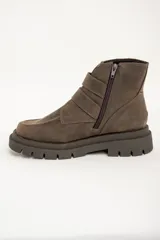 Botas cortas de cuero color visón con suela track, cierre lateral y doble tira con hebillas doradas.